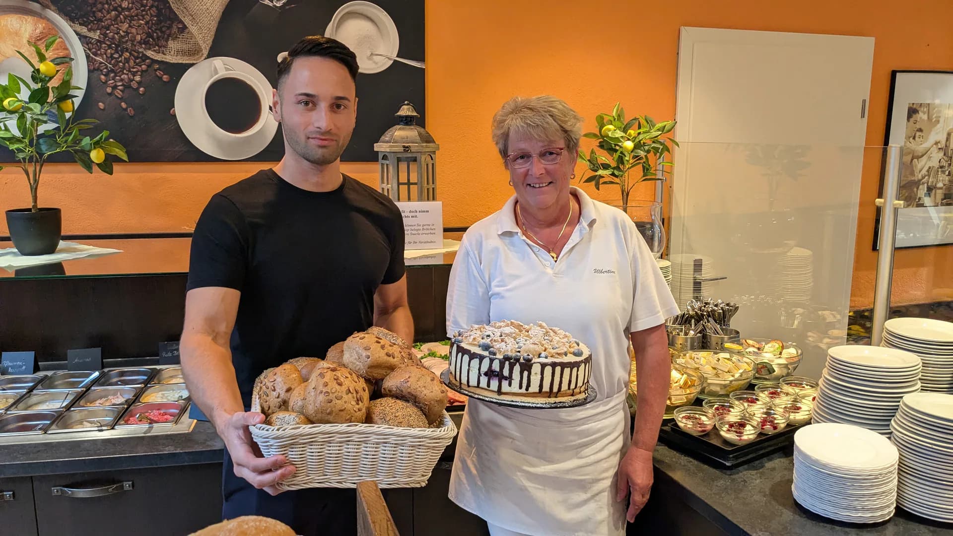 MDR-Morgenreporter Nils Sänger und eine Mitarbeiterin des Schlemmercafés mit frischen Brötchen und einer Torte