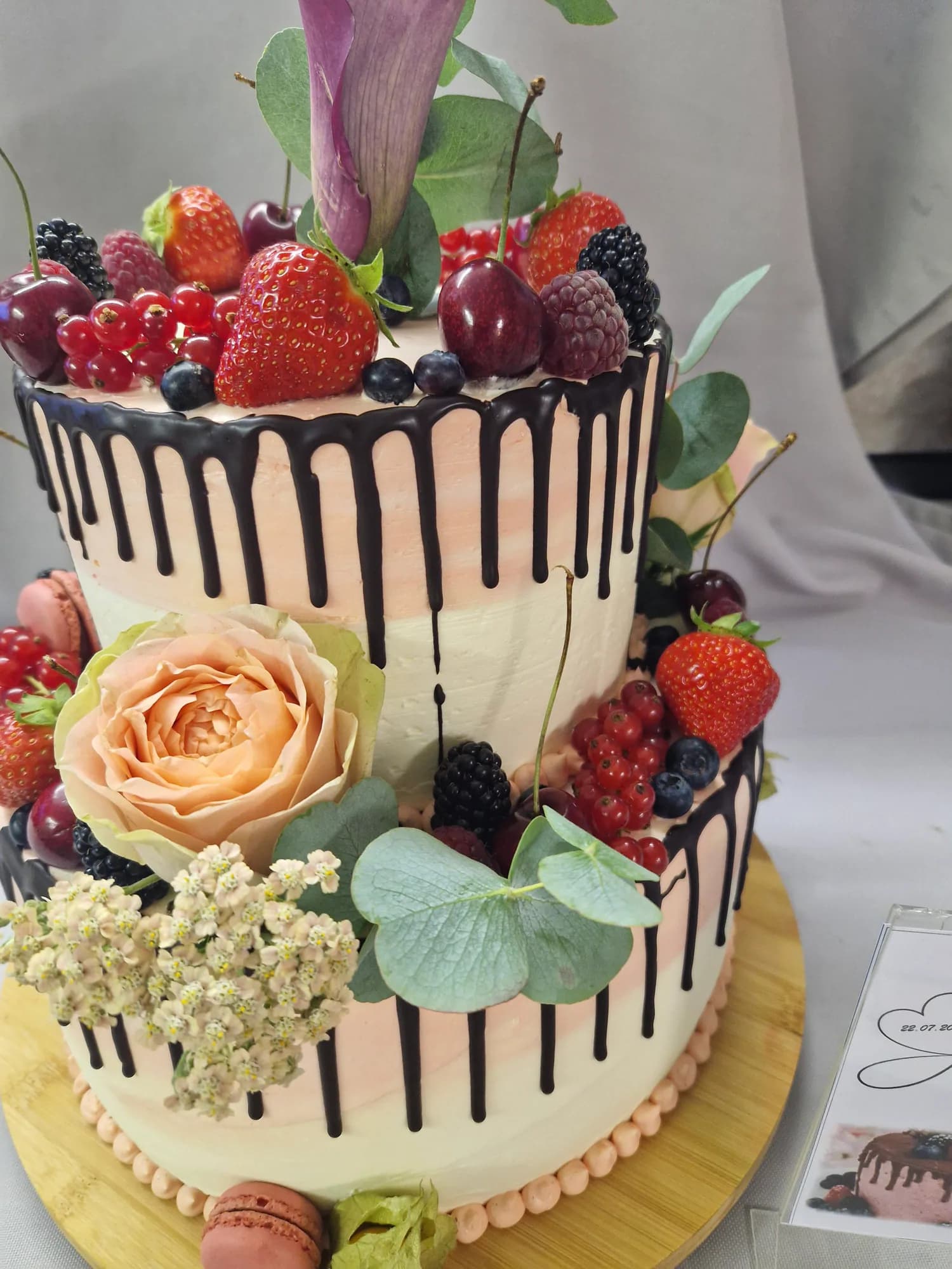 Mehrstöckige Hochzeitstorte mit Beeren und rosafarbener Blüte